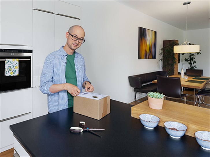 Kunde klebt Paketmarke Zuhause auf Paket.